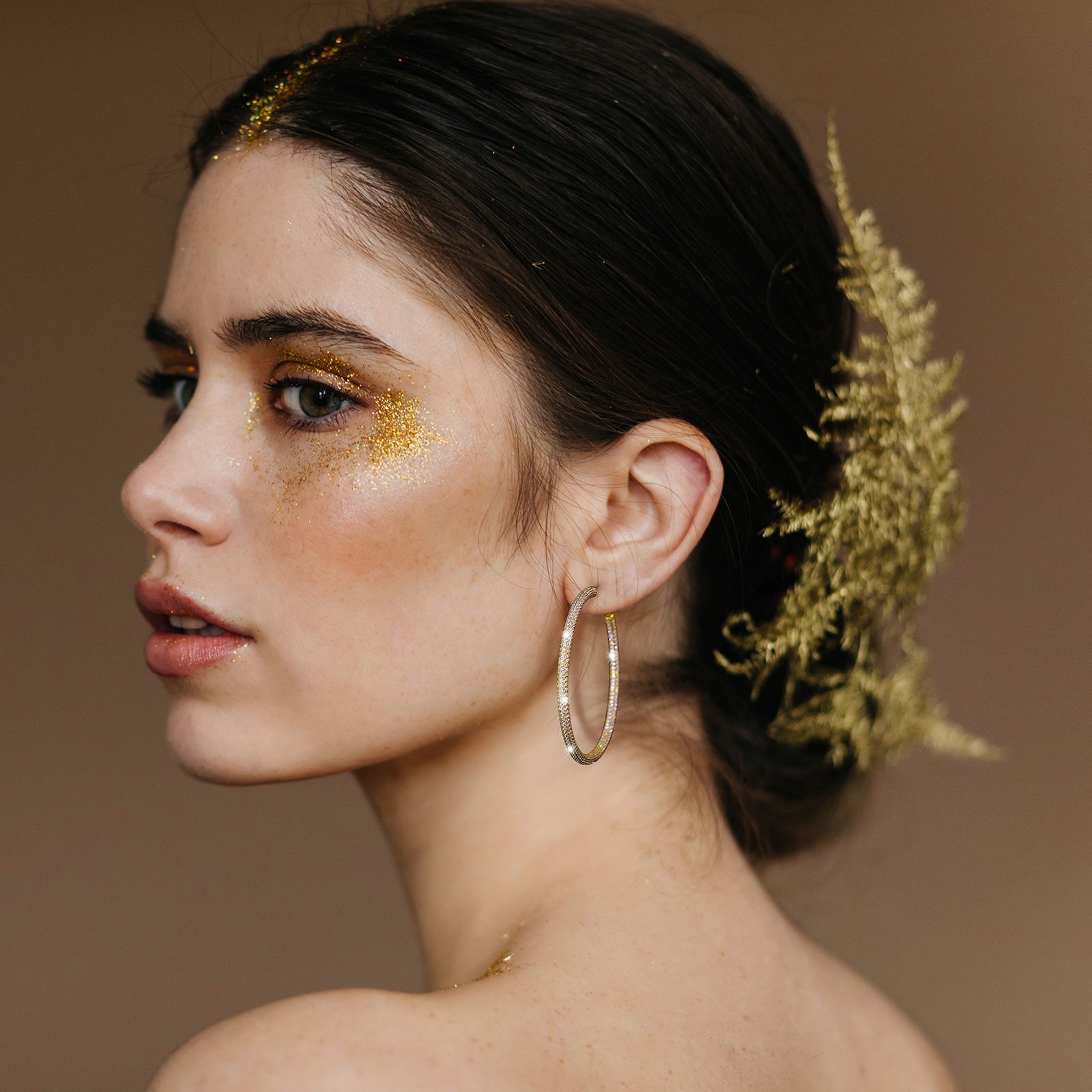 Close-up portrait of charming woman wears golden earrings. Studi